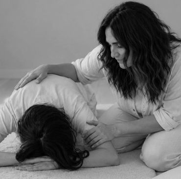 A woman comforting another woman who is lying down.