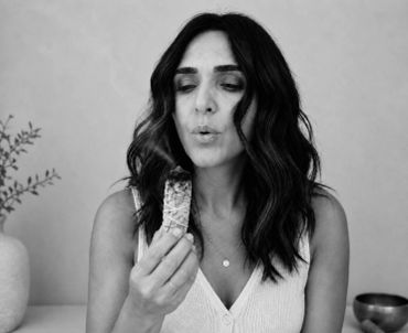 Woman blowing on food with closed eyes.
