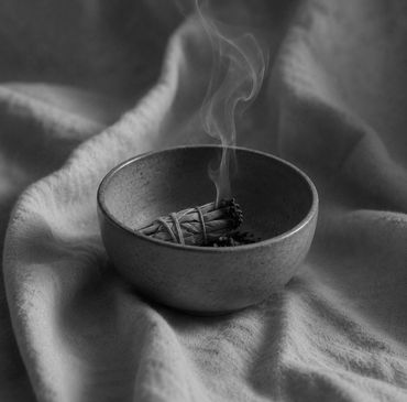 Burning sage in a small bowl with smoke rising.