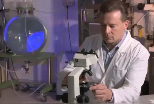 Scientist in a lab adjusting a microscope for research.