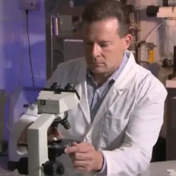 Scientist adjusting a microscope in a lab setting.