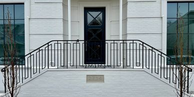 Modern white entrance with black door and railing.