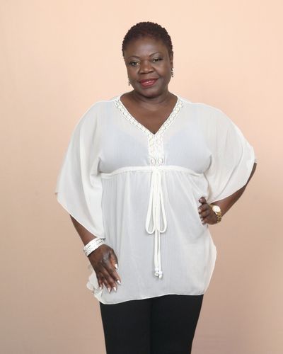 Confident woman in a white blouse and black pants posing with a smile.