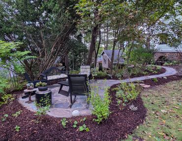 A cozy garden seating area with chairs and a small table surrounded by greenery.