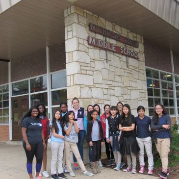 Group of middle school students posing outside their school building.