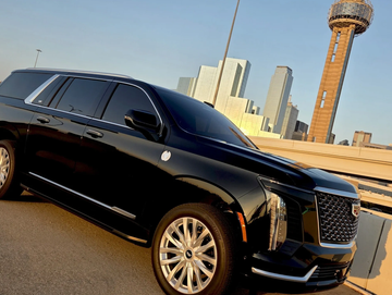 Black luxury SUV parked near cityscape at sunset.