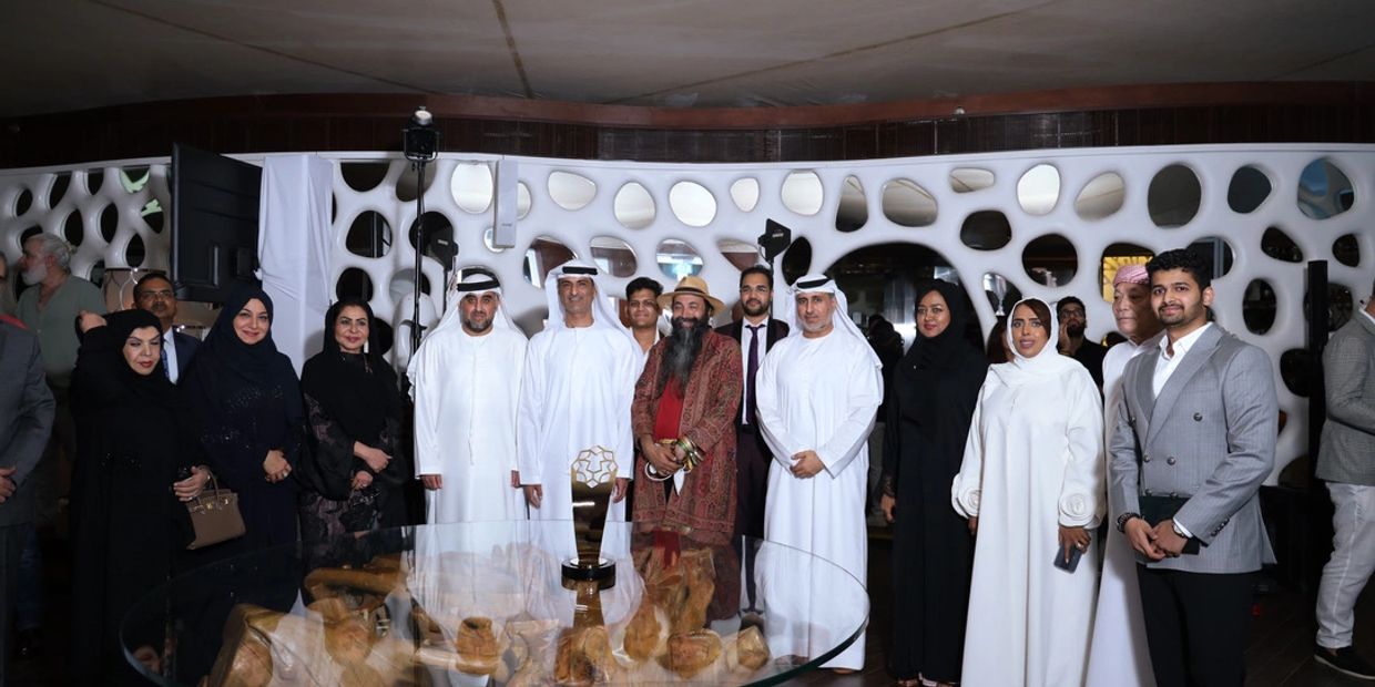 Group of people posing indoors with a trophy on a glass table.