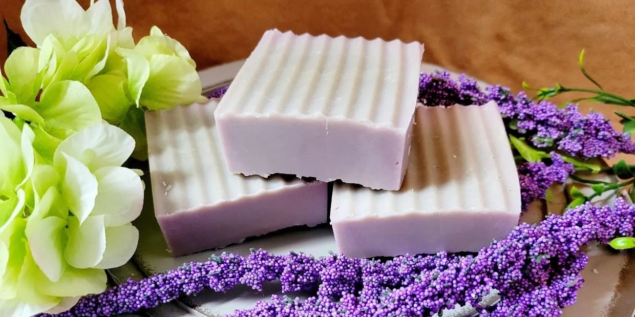 Three lavender soaps with flowers on a plate.