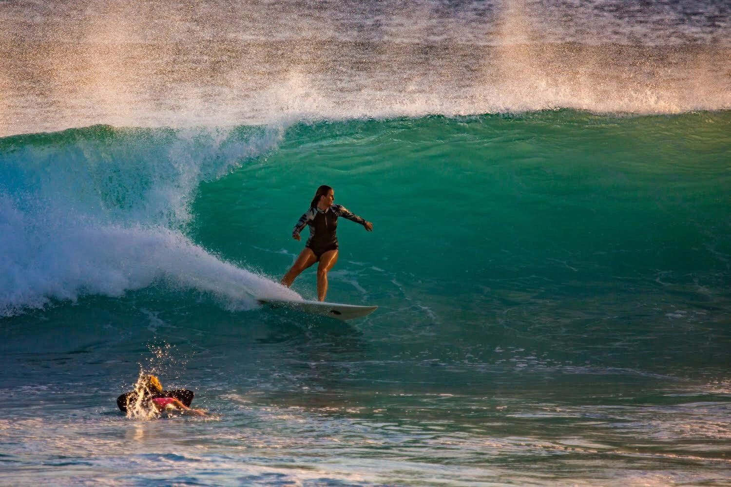 Female surfer going back side on a head high wave, determined to make the section