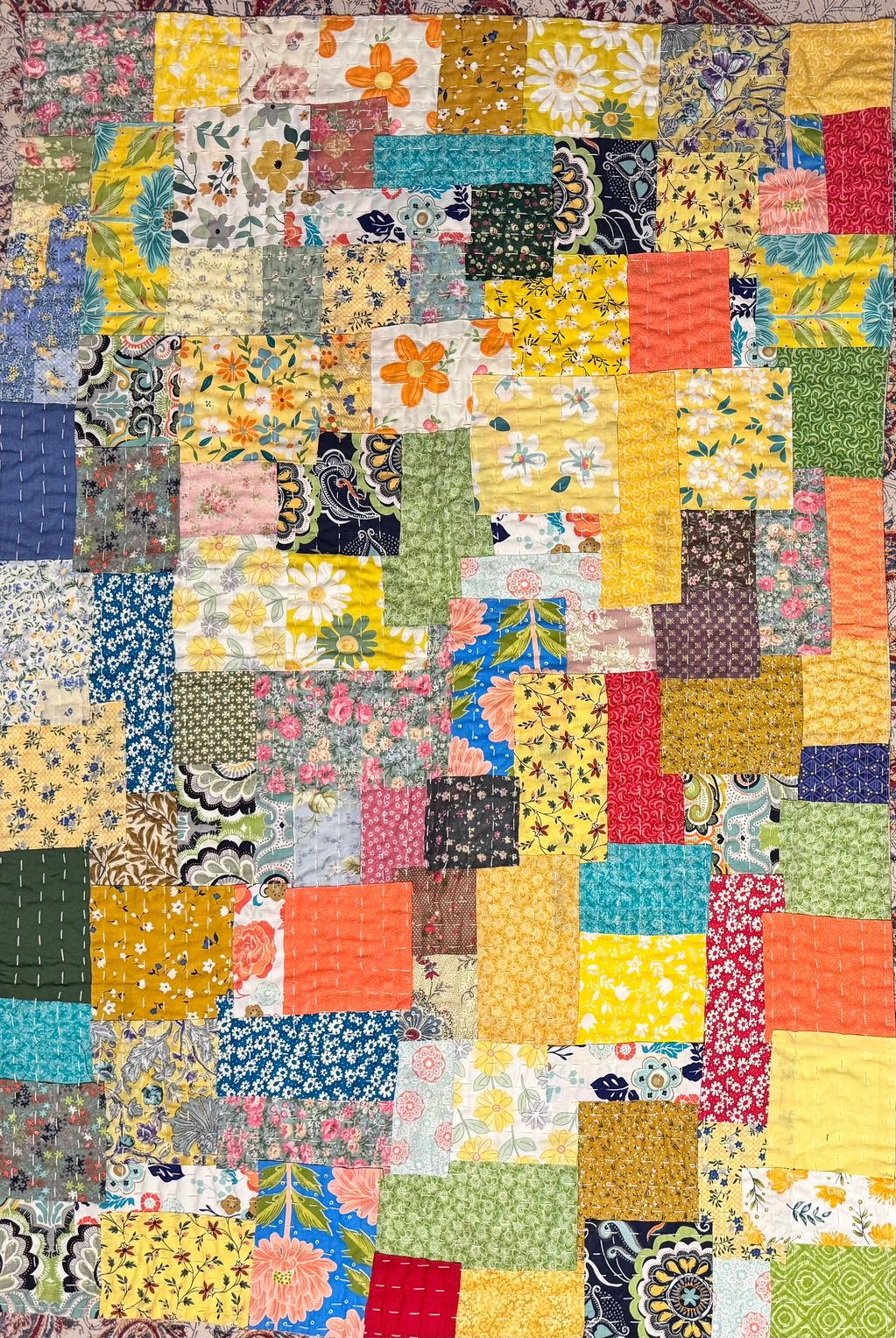 Colorful patchwork quilt with floral and geometric patterns.