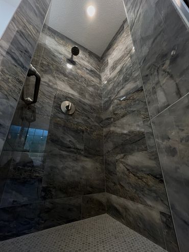 Modern shower with dark marble tiles and a built-in bench.