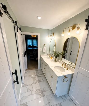 Modern bathroom with marble floor, double sink vanity, and sliding barn door.