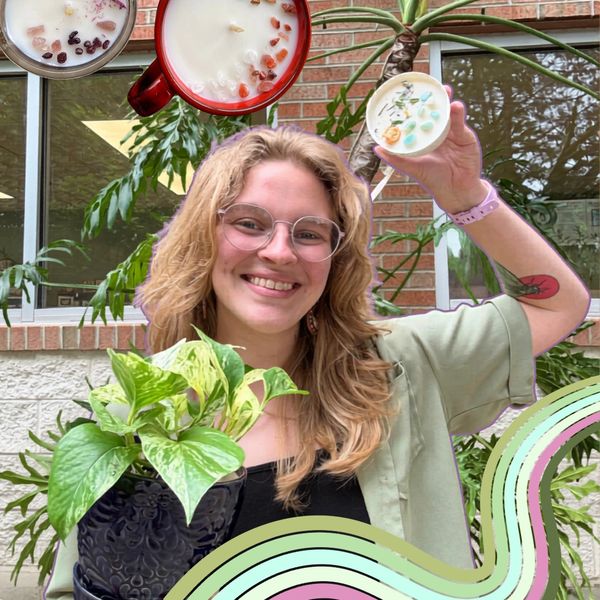 Smiling woman holding a potted plant and a candle, surrounded by greenery and colorful designs.