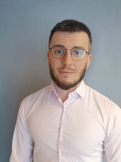 Man with glasses and beard wearing a light pink shirt.