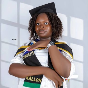 Young woman in graduation attire posing confidently with a diploma.