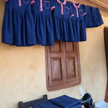 Blue and pink dresses hanging above a sewing machine.