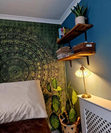 Cozy bedroom corner with mandala tapestry and warm lighting.