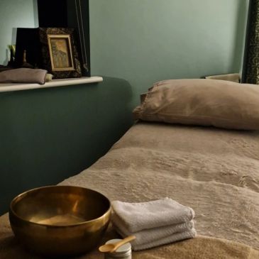 Cozy massage or spa room with a bowl, towels, and soft pillows.