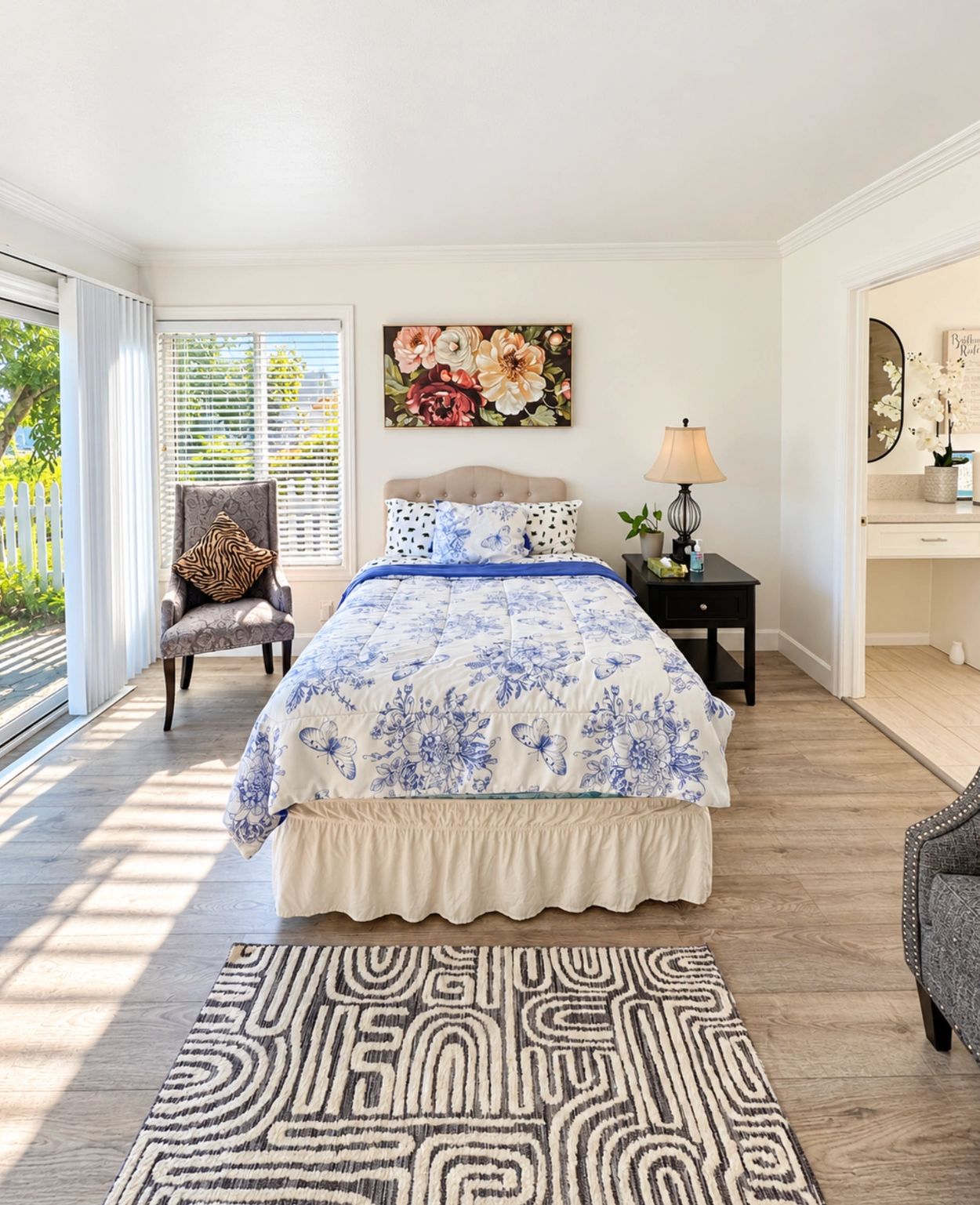 Bright bedroom with a floral bedspread and armchair.