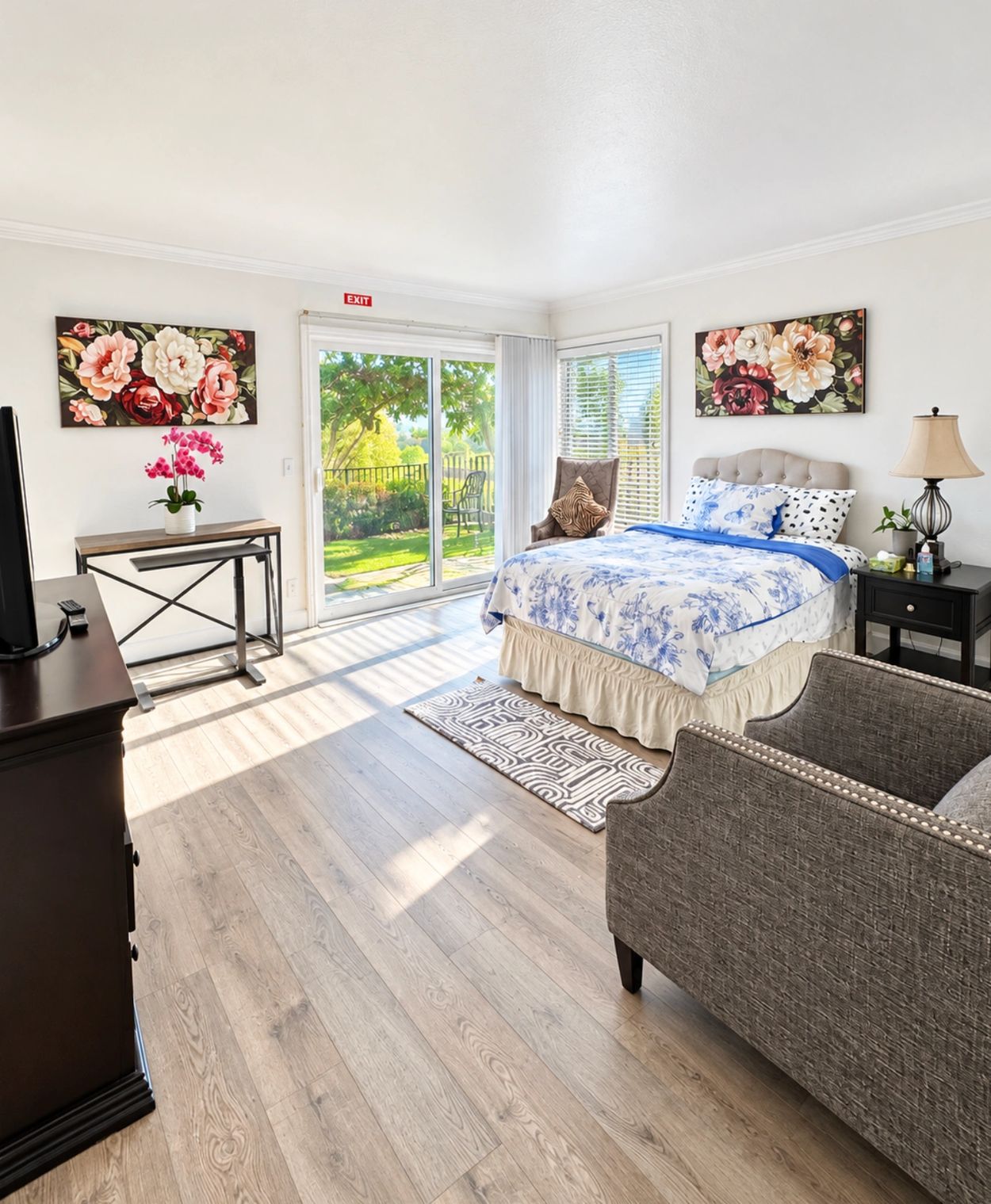 Bright bedroom with floral paintings and sliding glass door.