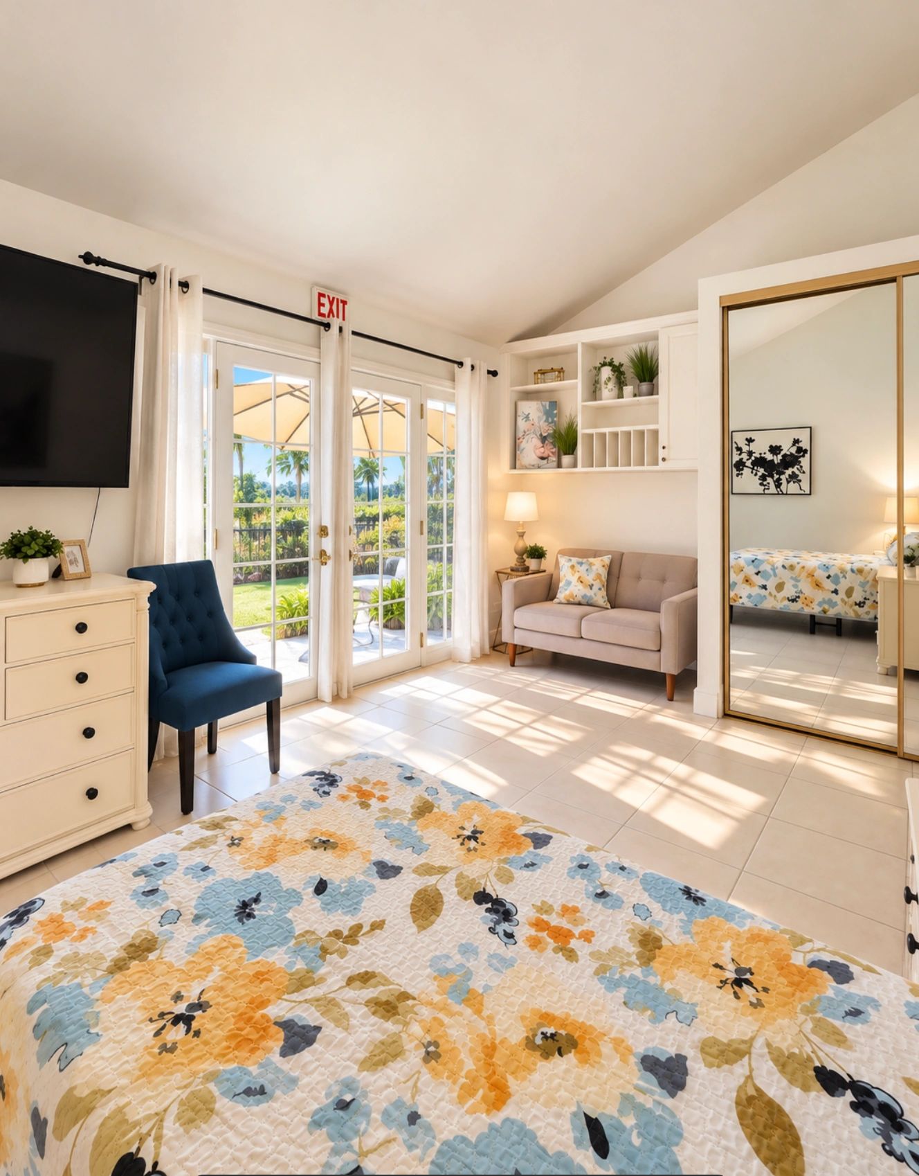 Bright bedroom with floral bedspread and patio doors.