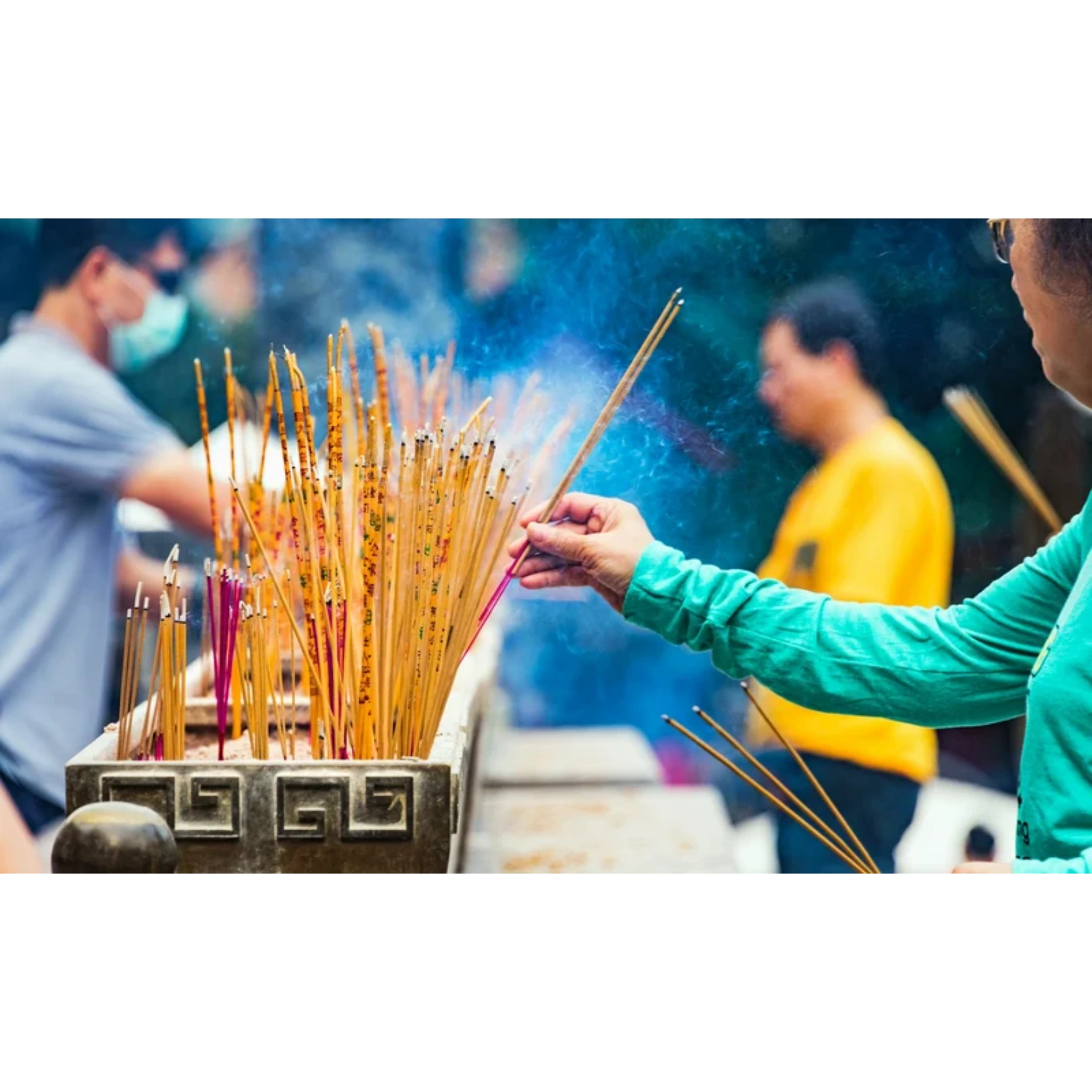 Hands resting on a yoga mat near burning incense sticks.