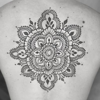 Intricate black mandala tattoo on upper back.