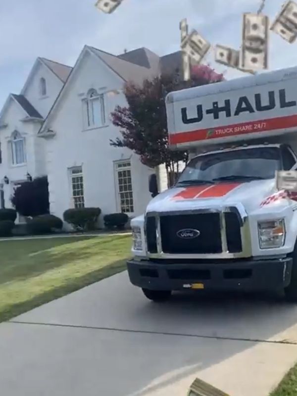 A U-Haul truck parked in front of a house with money flying in the air.