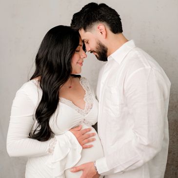 Couple tenderly embracing with the woman visibly pregnant.