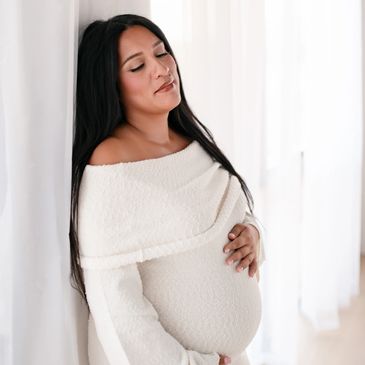 Pregnant woman in a cozy white sweater.