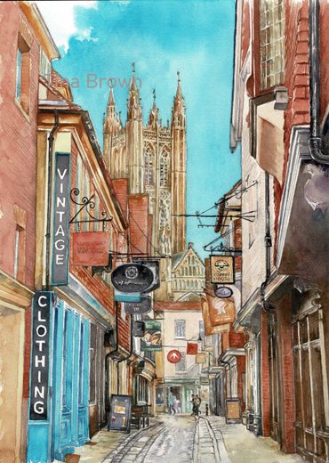 Watercolor painting of a narrow street with vintage shops and a cathedral in the background.