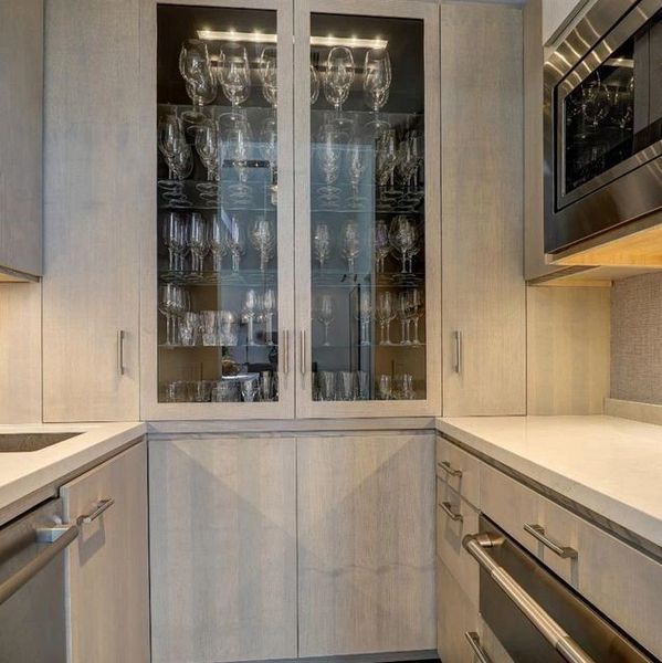 Modern kitchen with glass cabinet and stainless steel appliances.