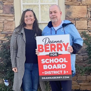 Two people holding a sign supporting Deanna Berry for School Board District 3.
