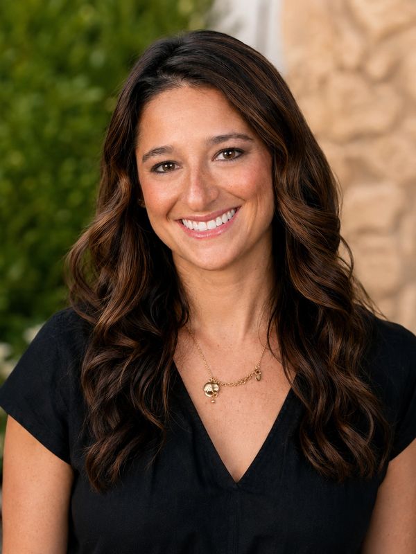 Smiling woman with long wavy hair outdoors.