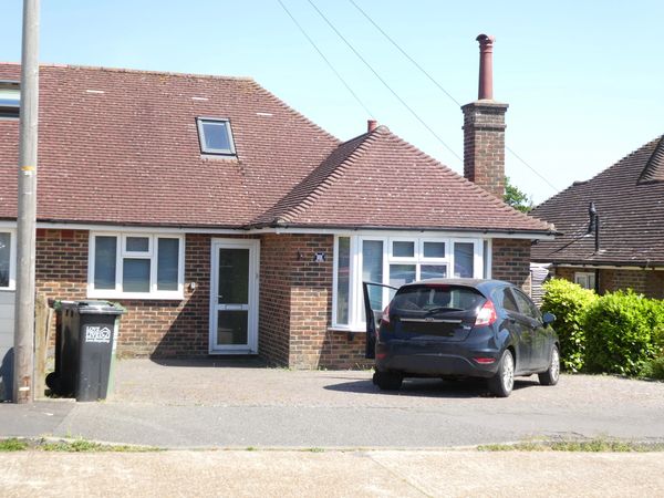 Semi-detached bungalow with a tall chimney pot and front elevation roof window.