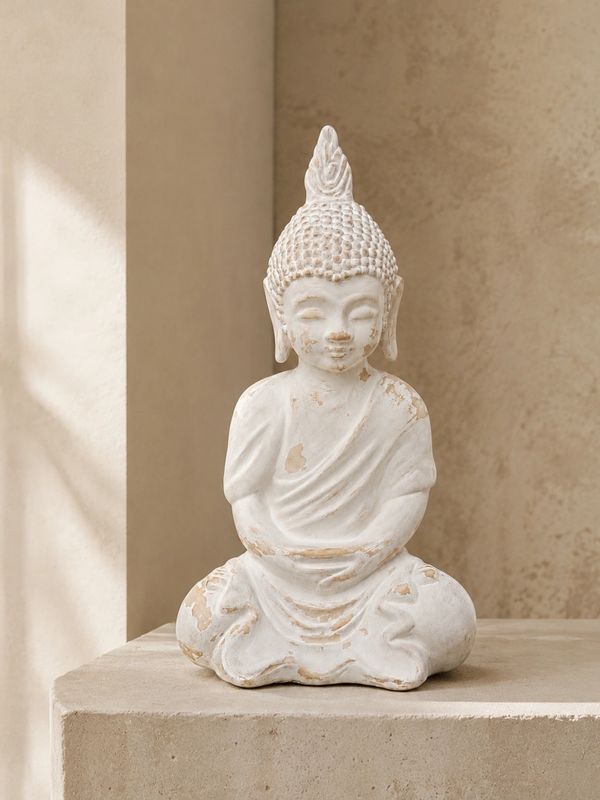 White Buddha statue in a serene, minimalist setting.