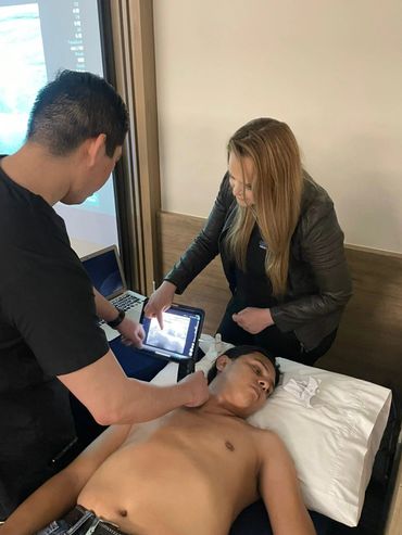 Two professionals use ultrasound on a patient's neck during examination.