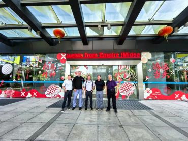 Group of six men standing outside a decorated building entrance.