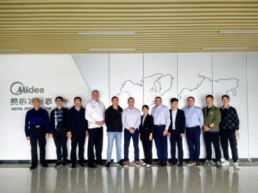 Group photo of business professionals in front of a Midea company logo.