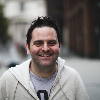 Smiling man in casual hoodie on a city street.