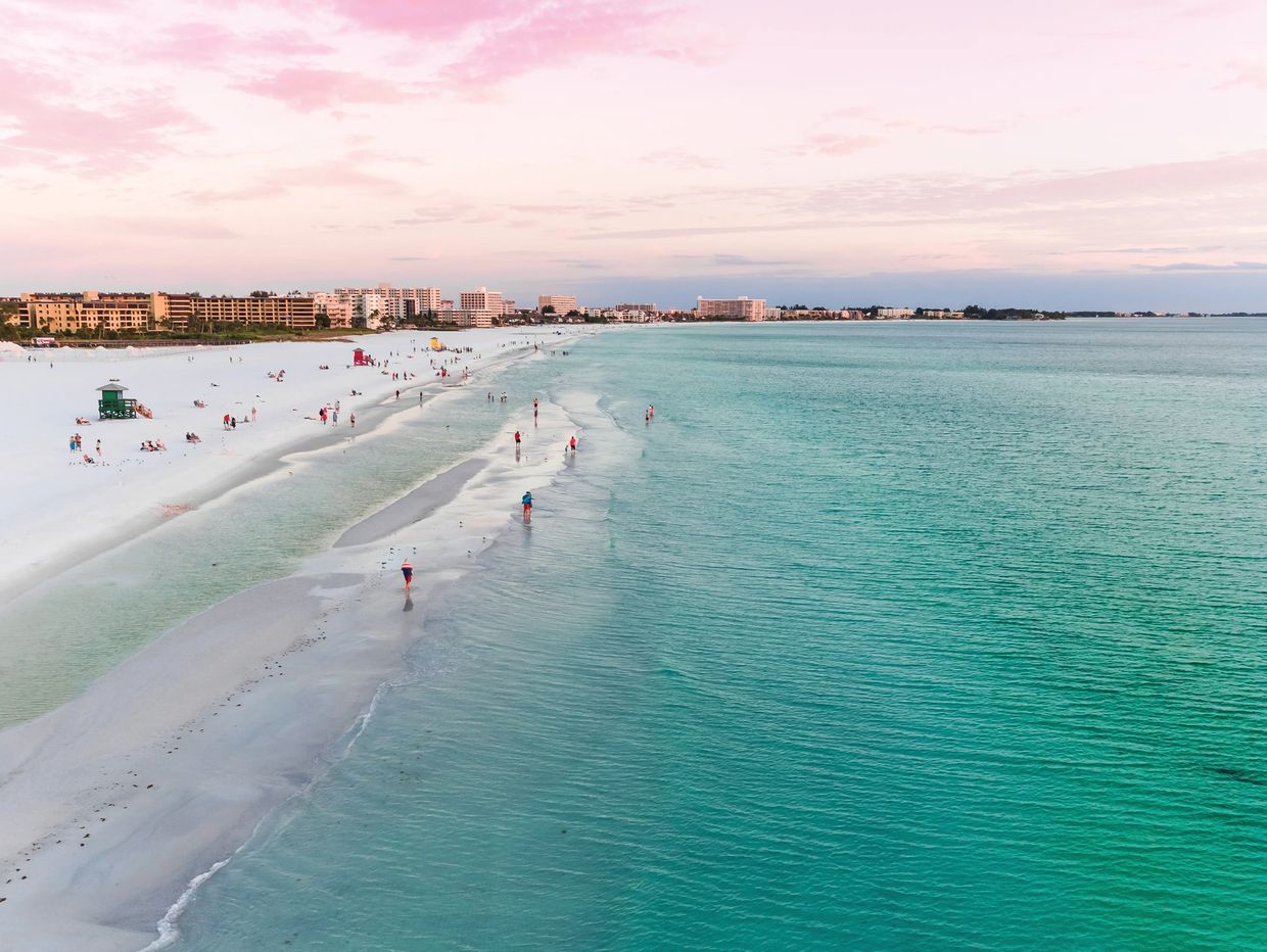 A serene beach with turquoise waters and a pink sky at sunset.