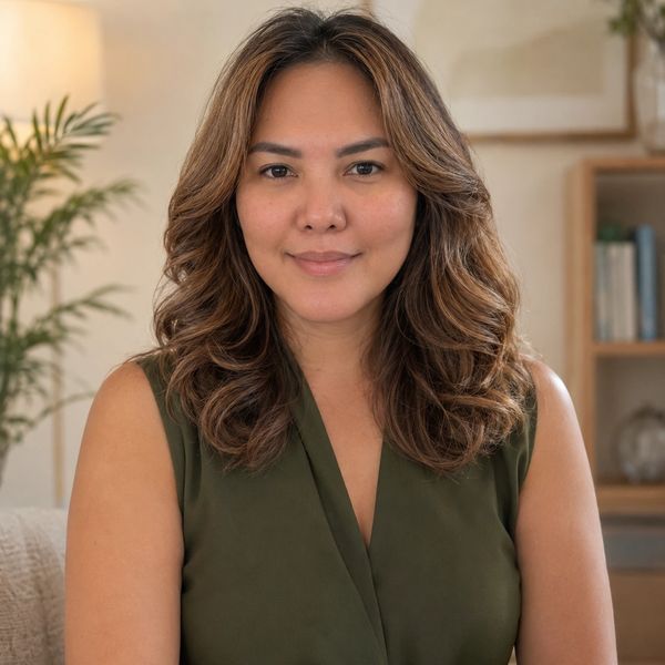 Woman with wavy hair in a green top, smiling gently.
