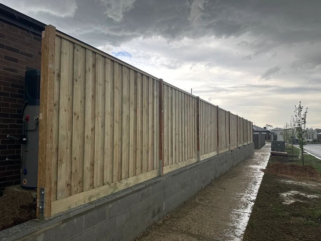 Exposed post capped timber paling fence on top of retaining wall.