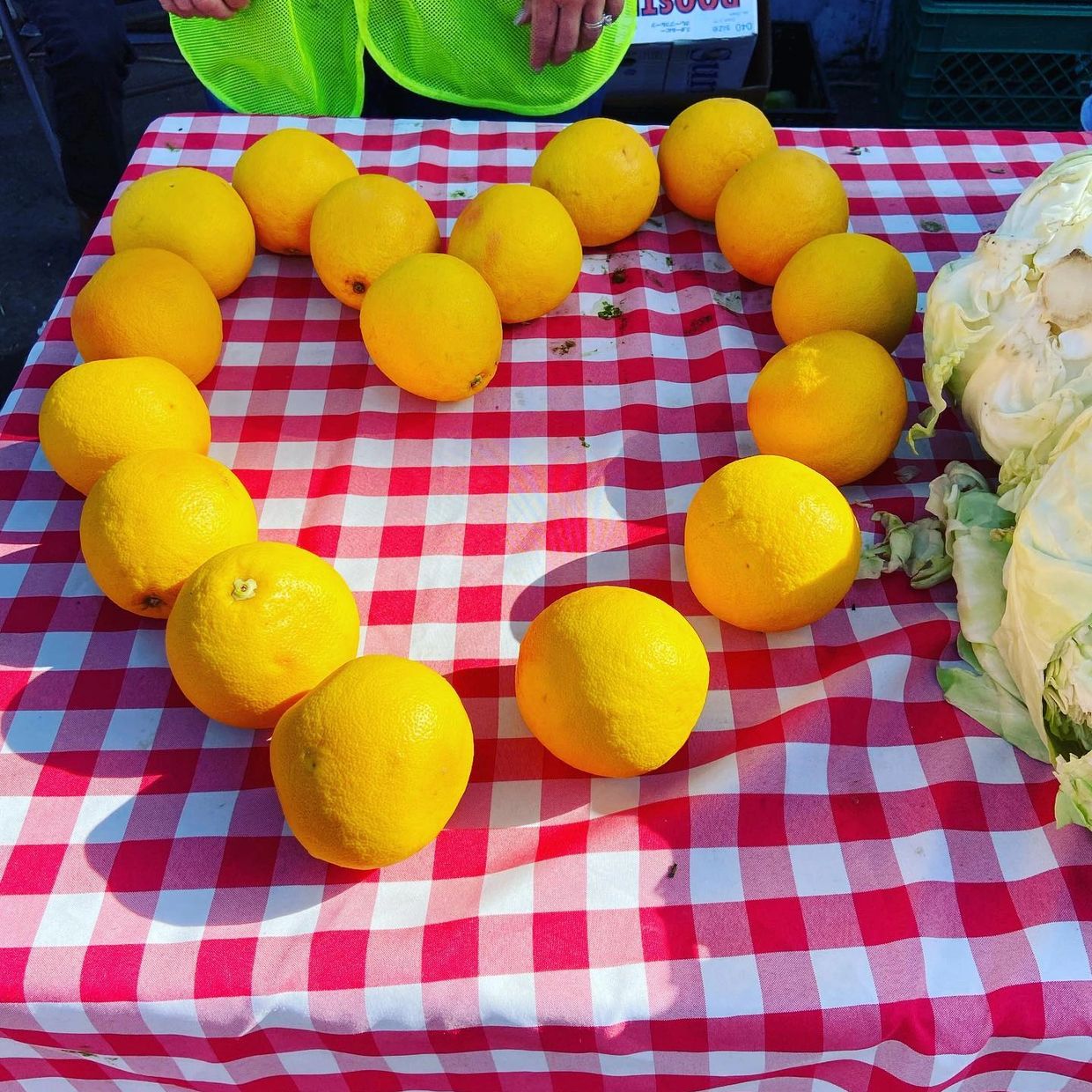 a bunch of grapefruits displayed in a heart shape on a red and white checkered tablecloth
