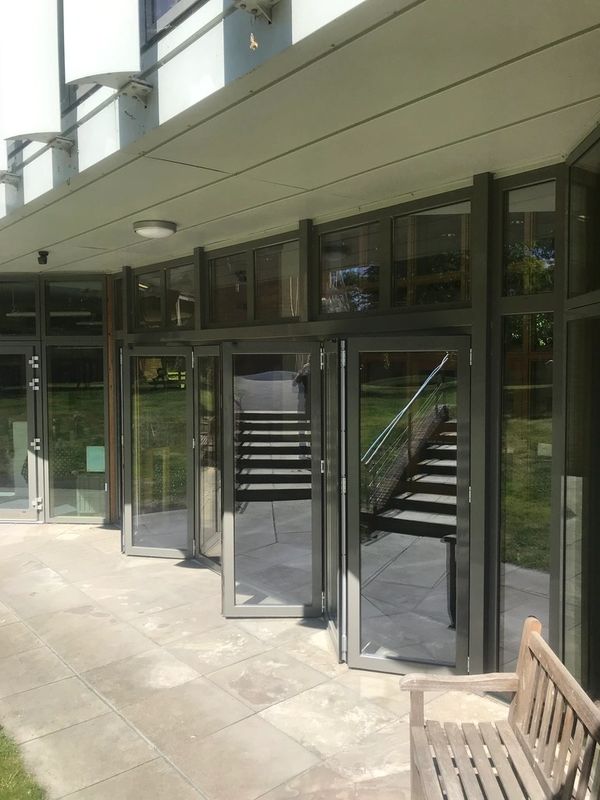 Glass doors with reflections of stairs outside a building entrance.