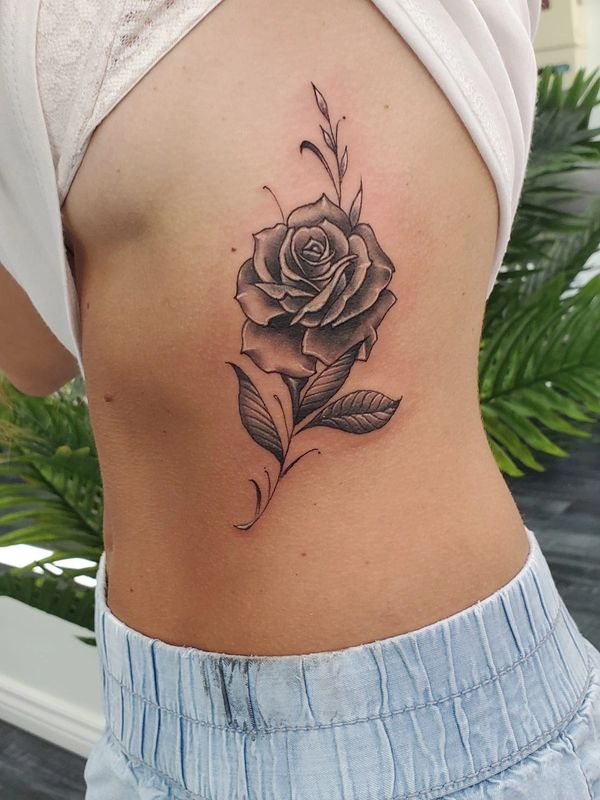 Cover up of initials on rib cage with black and gray rose by Ed Cuellar