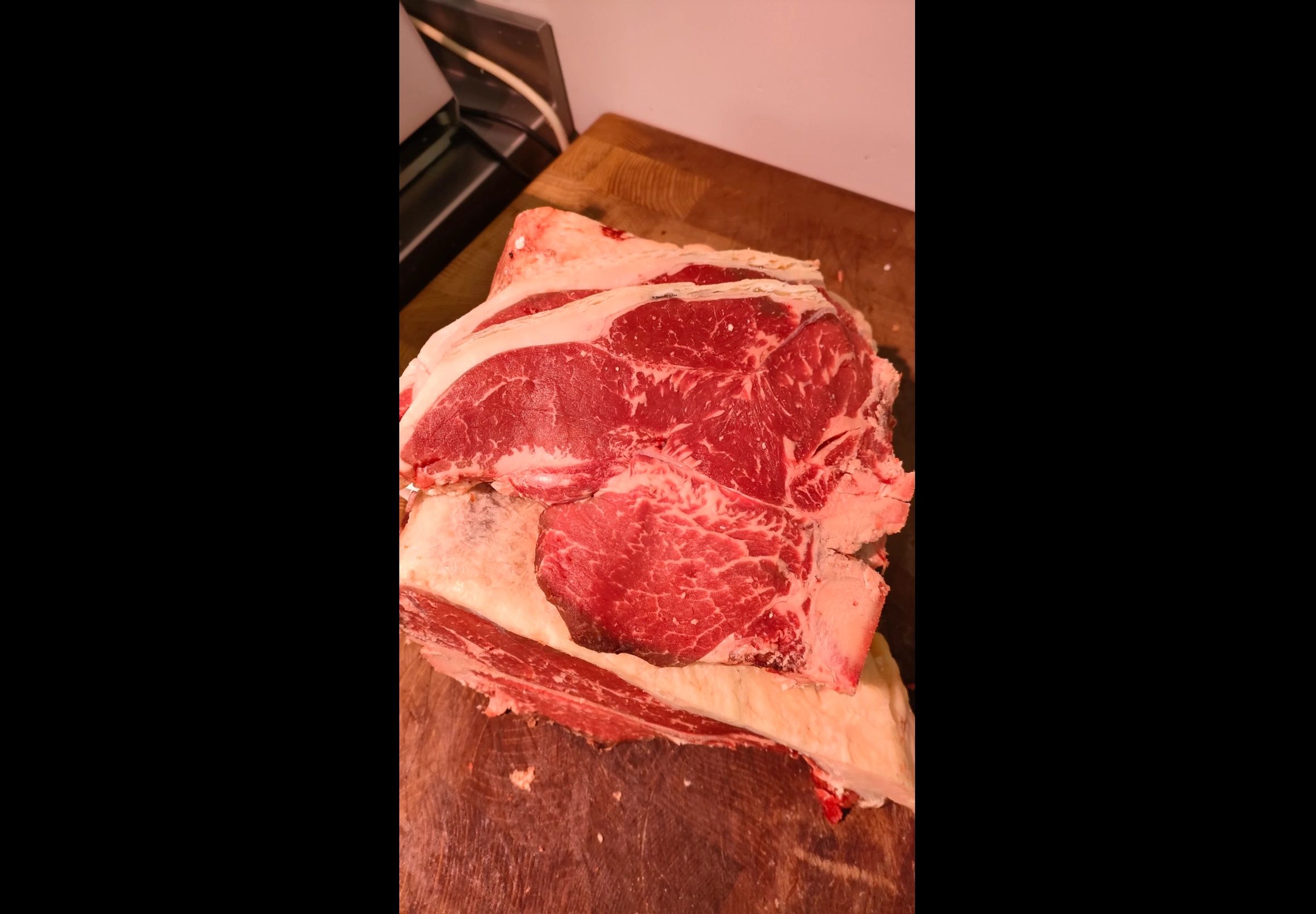 Close-up of raw marbled beef steak with fat on a wooden cutting board.