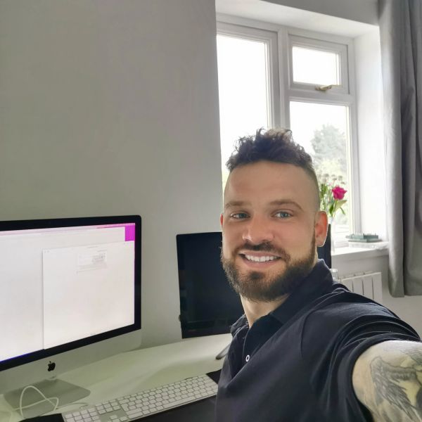 Man smiling while taking a selfie at his workspace.