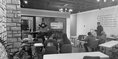 Group of people meeting in a comfortable sized room with stone walls. 