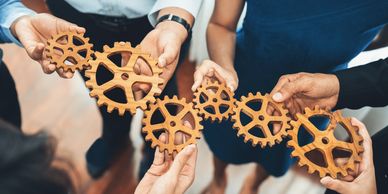 "People holding gears, symbolizing teamwork and collaborative effort."






